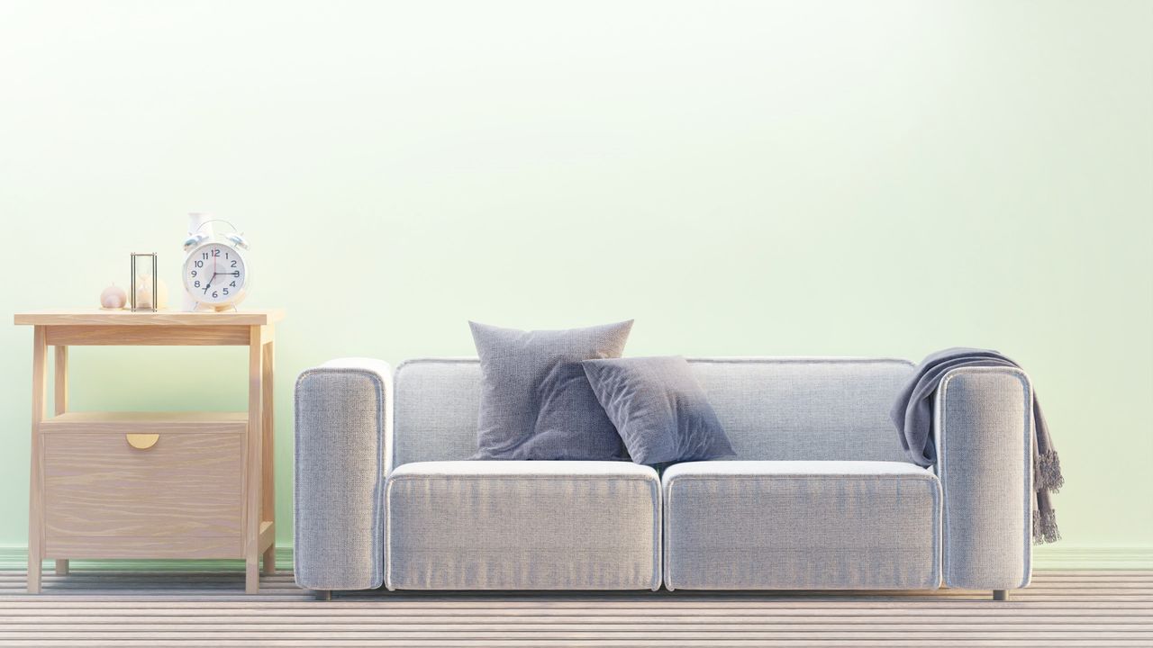 Home A cozy minimalist living room with a modern sofa, side table, and alarm clock.