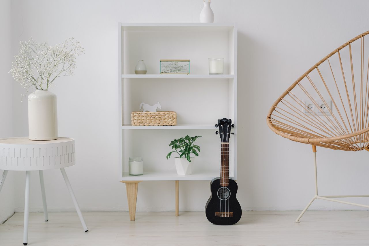 A modern minimalist living room setup featuring a ukelele, shelves, and stylish decor.